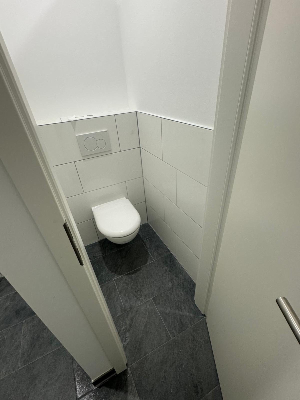 Neu gefliestes Gäste-WC in Weiß mit dunklem Bodenformat