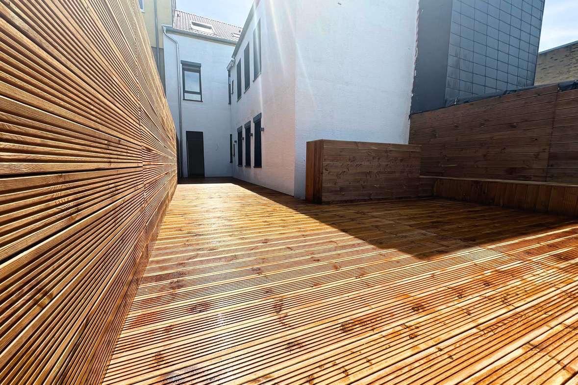 Neuer Holzbelag mit passendem Sichtschutz im Innenhof