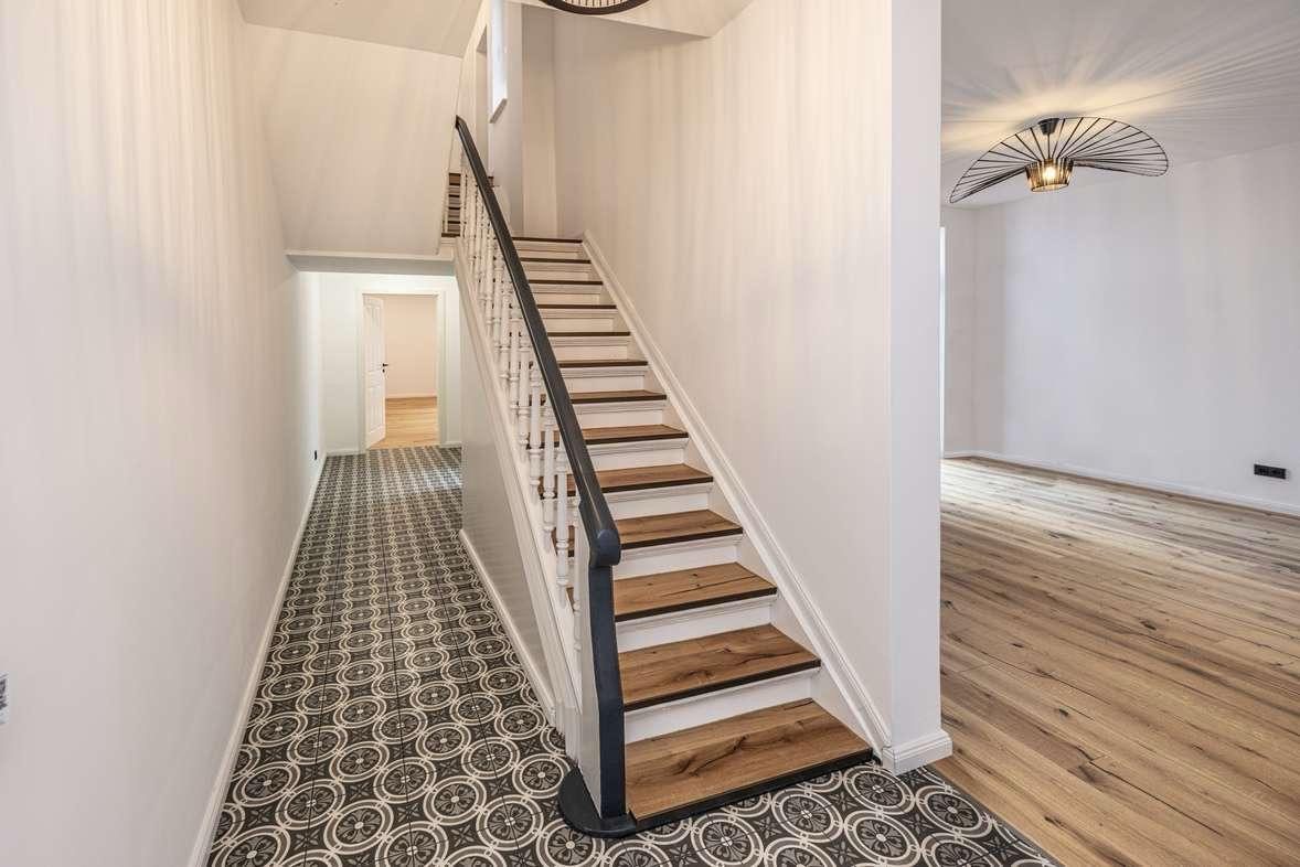 Saniertes Treppenhaus mit neuen Holzstufen und gemustertem Fliesenboden